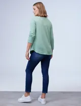 Blusa verde agua en tejido texturado, con cuello redondo y escote en V con aplique de aros metálicos.