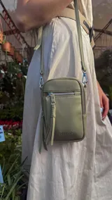 Bandolera compacta color rosado, con correa regulable y desmontable. Tiene apertura superior, bolsillo frontal con cierre y detalle de borla, y bolsillo trasero sin cierre. El interior está forrado en tela y cuenta con un bolsillo adicional.