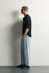 Jeans tapered wide fit de hombre, confeccionados en denim de algodón con efecto lavado en tono azul oscuro. Presentan diseño de cinco bolsillos, tiro medio, corte relajado y cierre frontal con cremallera y botón.
