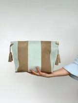 Cartera tipo sobre de cuero con diseño de franjas verticales en colores verde menta y marrón tostado. Cuenta con detalles de borlas colgantes en los laterales.