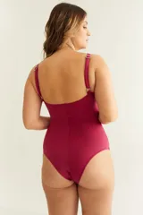 Malla entera color guinda con escote redondo cruzado, cut out en el abdomen, detalle de frunce y breteles finos regulables. Incluye una flor removible.