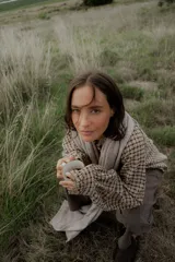 Camisa de manga larga con estampado cuadrillé en tonos marrones y negros, cuello alto con volados y puños elásticos.