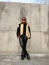 Campera de corderito con diseño de rayas verticales en colores beige y negro, con cierre frontal y detalles de ribete en color marrón.