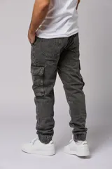 Pantalón jean gris oscuro de corte jogger con bolsillos cargo laterales y puños elásticos en los tobillos.
