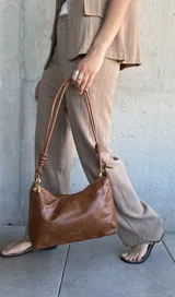 Pantalón de vestir color tostado con finas rayas verticales blancas, de corte palazzo y tiro alto.