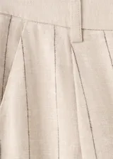 Pantalón recto color beige de tiro medio, con estampado de raya diplomática, trabillas para cinto y cierre frontal con gancho y cremallera.