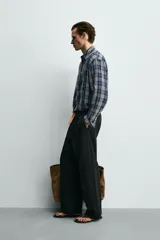 Camisa de corte relajado confeccionada en tejido fluido con mezcla de viscosa y acetato. Presenta un diseño a cuadros, cuello solapa, manga larga con puños abotonados, bolsillo plastrón en el pecho y cierre frontal con botones.
