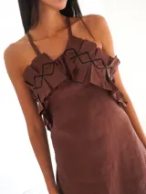 Vestido largo marrón de lino, con tiras para atar al cuello, escote con volados y detalles de bordado lineal, y tajos laterales en la falda.