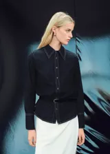 Camisa de denim oscuro con costuras en contraste, cuello camisero clásico, cierre frontal con botones y mangas largas con puños abotonados.
