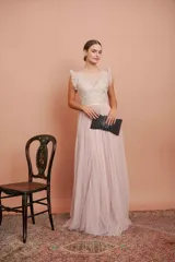 Vestido largo de fiesta color rosado con lunares blancos. Tiene cuerpo de micro tul bordado con volados en los hombros y falda de tul con forro. Incluye cinturón de raso al tono.