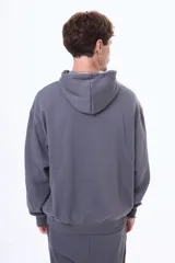 Buzo tipo canguro de felpa color gris, con capucha amplia, bolsillo frontal tipo canguro y puños acanalados.