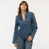 Blusa de jean de corte recto, con cuello polo, escote en V y bolsillo frontal en el pecho. Presenta mangas largas y un diseño de calce holgado.