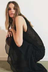 Falda midi negra de tiro medio con superposición de tejido transparente con diseño estampado y aplicación de abalorios a tono. Presenta bajo asimétrico con volantes y forro interior negro.