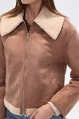 Campera estilo aviador color marrón claro, con cuello y forro de corderito color beige. Presenta cierre frontal y puños y ruedo con terminación de corderito.