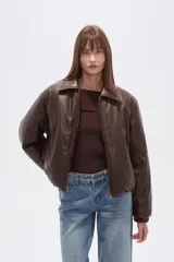 Campera estilo bomber de eco-cuero color marrón oscuro, con cuello camisero, cierre frontal y puños y cintura elásticos.