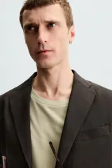 Blazer regular fit color marrón oscuro confeccionado en tejido de lino. Tiene cuello con solapas de muesca, manga larga con puño abotonado, bolsillo de vivo en el pecho, bolsillos de solapa en la cadera, bolsillo interior, bajo con aberturas en la espalda y cierre frontal con botonadura.