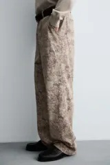 Pantalón de corte relajado confeccionado en tejido ligero de algodón con estampado abstracto de efecto lavado. Presenta cintura elástica, bolsillos frontales y bolsillos traseros de plastrón, con cierre frontal de cremallera y botón.