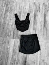 Conjunto de dos piezas confeccionado en tela satinada color azul vibrante. Incluye un top tipo corset con escote cuadrado y una minifalda ajustada de tiro alto.
