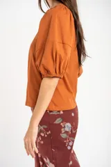Remera de algodón negro con mangas cortas abullonadas, cuello redondo y costura central frontal.