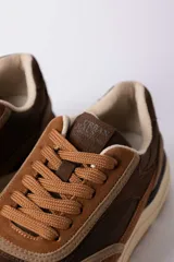 Championes urbanos Urban Haus modelo Julen, con diseño de paneles en tonos verde oliva y beige. Presentan una combinación de texturas en gamuza y material sintético, con suela de goma dentada en color caramelo.