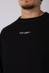 Buzo de cuello redondo y manga larga, confeccionado en tejido de punto acanalado de color negro. Presenta un diseño minimalista con un pequeño logo estampado en el pecho y un corte relajado.