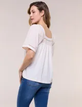 Blusa de corte holgado color marfil, confeccionada en mezcla de modal y algodón, con escote cuadrado y mangas cortas adornadas con detalles de puntilla calada.