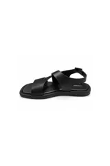 Sandalias planas de cuero color negro, con tiras cruzadas en el empeine, diseño abierto y tira en el talón con hebilla metálica dorada para ajuste.