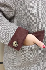 Campera de paño de lana en color beige jaspeado, con diseño oversize. Presenta detalles en pana color marrón chocolate en los puños y en las tapas de los bolsillos frontales. Cuenta con cierre frontal de botones grandes y cuello alto.