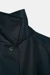 Chaqueta corta de cuello subido y manga larga con trabilla y botón. Cuenta con bolsillos de vivo en el delantero y cierre frontal con botones.