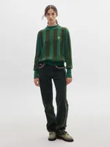 Pantalón de pana roja con corte holgado y tiro medio. Presenta una línea dorada a lo largo de la pierna.