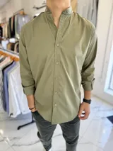 Camisa de manga larga color verde militar con cuello mao y cierre frontal de botones.