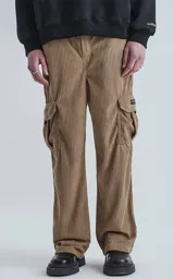 Pantalón cargo de corderoy color arcilla (marrón claro/beige), de calce regular y tiro alto con elástico fruncido. Presenta seis bolsillos, incluyendo dos bolsillos cargo con solapa en las piernas.