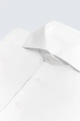 Camisa blanca de manga larga con cuello italiano abierto y cierre frontal de botonadura.