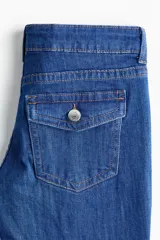 Pantalón jean de denim azul elastizado, de tiro bajo y corte ajustado con botamanga acampanada. Presenta diseño clásico de cinco bolsillos y cierre frontal con botón y cremallera.