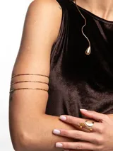 Brazalete dorado de metal con diseño de triple aro delgado.