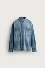 Camisa relaxed fit confeccionada en denim ligero de algodón, con cuello solapa, manga larga con puño abotonado, dos bolsillos de parche en el pecho con solapa y cierre frontal de botones. Presenta un efecto de lavado desgastado.