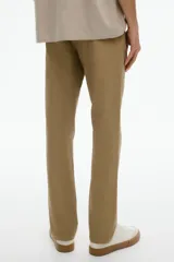 Pantalón de algodón color beige, estilo chino, con corte slim fit. Presenta cierre y botón frontal, bolsillos laterales al bies y bolsillos insertados con botón en la parte trasera.