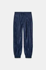 Pantalón de tiro alto de tela satinada color azul marino, con bolsillos frontales, cintura ajustable con cordones y puños elásticos en los tobillos.
