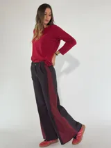 Pantalón de denim gris oscuro con paneles laterales en color bordó y corte acampanado.