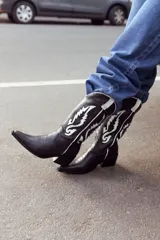 Botas texanas negras de cuero con bordados blancos y taco bajo.