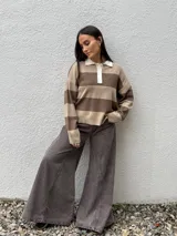 Sweater tipo chomba de tejido bremer con diseño de rayas horizontales en color marrón y celeste. Presenta cuello polo en color crema con cierre frontal de botones y mangas largas.