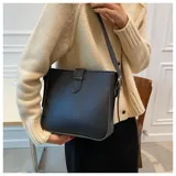 Cartera tipo bandolera de diseño estructurado, color negro, con cierre de solapa frontal mediante trabilla y correa ajustable para el hombro.