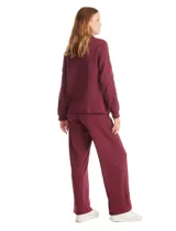 Campera bordó de modal con cuello solapa, cierre frontal con botones metálicos y bolsillos laterales. Presenta mangas largas con detalles labrados en los antebrazos y puños ajustados.