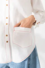 Camisa de lino color tostado, con cuello alto con volados, cierre frontal de botones y mangas largas con puños con volados.