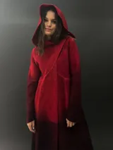 Tapado rojo con capucha, confeccionado en lana merino teñida con técnica tie-dye. Tiene corte recto, largo, bolsillos laterales y cierre cruzado con broches a presión ocultos.