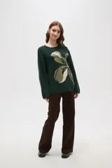 Sweater de punto jacquard con diseño floral abstracto en tonos tierra sobre fondo negro, de corte holgado, cuello redondo y manga larga.