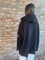 Campera de corderito color verde oscuro, con diseño holgado, cuello alto y manga larga. Presenta una etiqueta de cuero sintético en la manga.