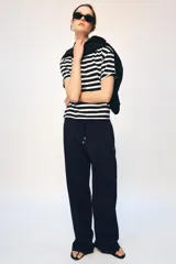 Camiseta de algodón con diseño de rayas horizontales en blanco y negro, cuello redondo y manga corta. Presenta una pequeña aplicación metálica con las letras ZA en el centro del pecho.