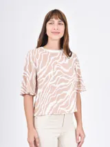 Blusa de mangas cortas con volados, color beige con estampado de líneas onduladas blancas.