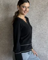 Remera blanca de manga larga con cuello en V y costuras decorativas en contraste. Incluye un lazo ajustable en el cuello con herraje metálico circular.